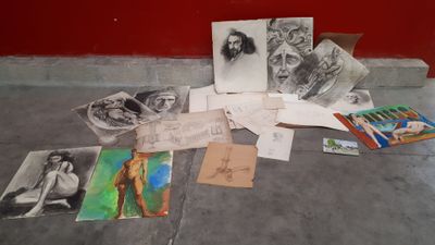 une pile de dessins posée par terre près d'un mur rouge