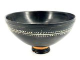 a black bowl with white designs on it on a white surface