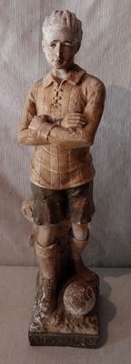 une statue en bois représentant un homme coiffé d'un chapeau