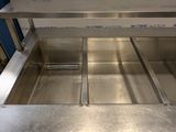 a stainless steel sink in a kitchen with a blue wall