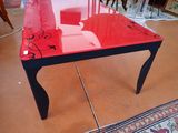 a glass table with a red glass top and black legs