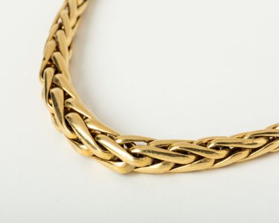 a close up of a gold necklace on a white surface