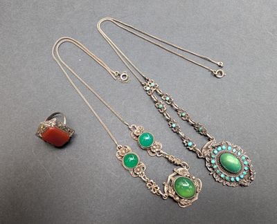 trois colliers ornés de turquoises et de pierres rouges, posés sur une table