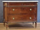 a wooden chest of drawers with marble top on a hard wood floor