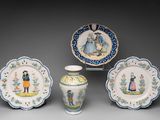Plusieurs pièces de porcelaine sont exposées sur un support gris