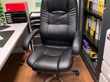 a black office chair sitting in front of a computer desk