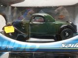 une petite voiture verte dans une boîte, avec une étiquette de prix dessus