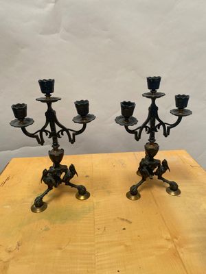 une paire de chandeliers anciens en laiton posés sur une table en bois, sur fond blanc