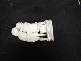 a small statue of a person laying down on a black surface