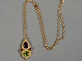 un gros plan sur une chaîne en or avec un pendentif vert et violet