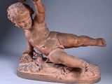 statue of a boy laying on a rock with a bird in his hand