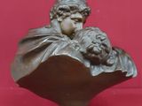 buste en bronze représentant un homme tenant un chien, posé sur un fond rouge