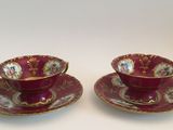 pair of red and gold cups and saucers with floral designs