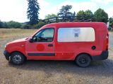 a red van parked in a field with trees in the background