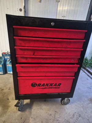 un gros plan d'une boîte à outils rouge posée sur un chariot dans un garage