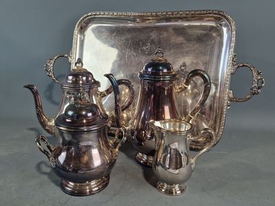 trois théières en argent et un plateau posés sur une table