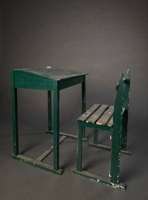two green wooden chairs and a table against a gray background