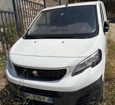 une petite camionnette blanche garée devant une clôture