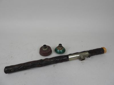 une pipe avec un manche en bois à côté d'une petite bouteille