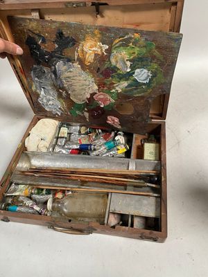 une personne tenant un pinceau et une palette dans une boîte en bois