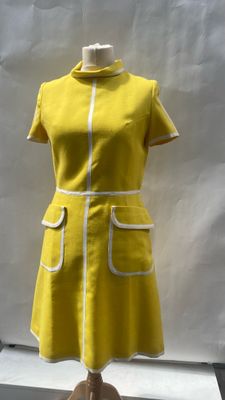 yellow dress with white trim on mannequin base in front of a white backdrop
