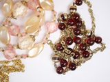 two necklaces with pearls and gold chains on a white surface