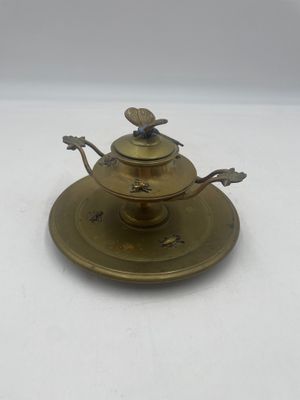 une assiette en laiton ornée d'un oiseau, surmontée d'une soucoupe