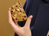 someone is holding a piece of jewelry in their hand and wearing a suit