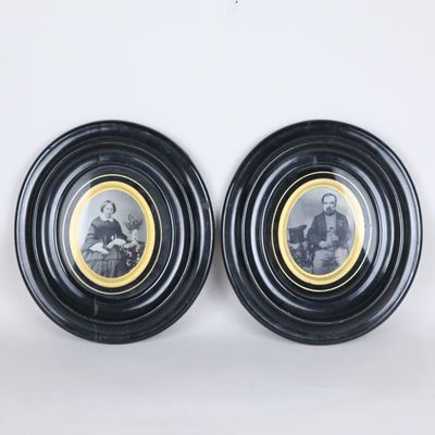 une paire de portraits, encadrés en noir et or, représentant un homme et une femme