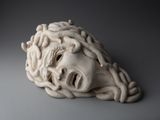 sculpture représentant une tête d'homme avec une tête de serpent au milieu
