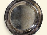assiette en argent plaqué avec un bord festonné sur fond blanc