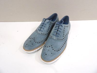 pair of blue shoes on a white table with a wall in the background