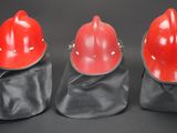 three red hard hats sitting on top of each other on a black surface