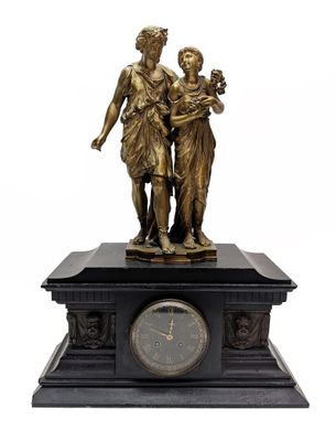une statue en bronze représentant une femme et un enfant, avec une horloge