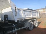 a white dump truck that is parked in the dirt