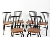 six chaises de salle à manger noires et en bois posées sur un sol blanc