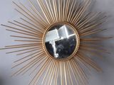 un miroir doré en forme d'étoile accroché au mur à côté d'un vase