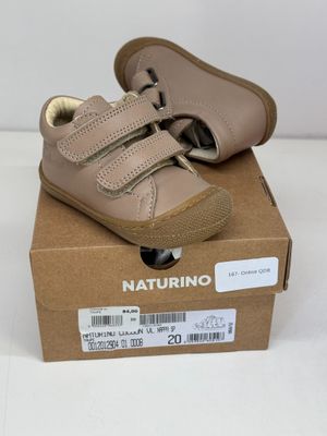 des chaussures de bébé en cuir beige dans une boîte posée sur une surface blanche