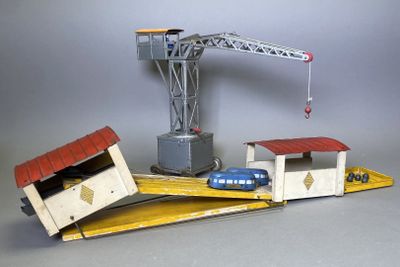 une grue miniature située à côté d'un immeuble et d'une voiture
