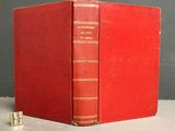 an old red book sitting on top of a white table