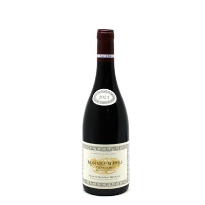 the bottle of red wine is sitting on a white surface