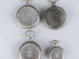 three silver pocket watches and a silver keychain on a table