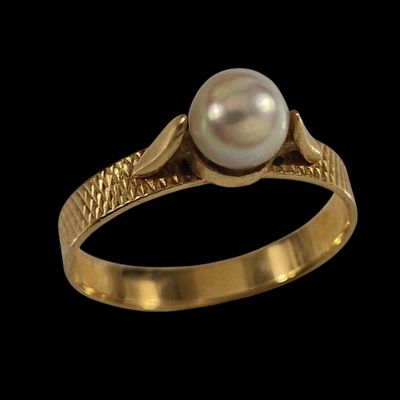 gros plan d'une bague en or contenant une perle