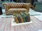 a glass table with books on it and a leather couch in the background