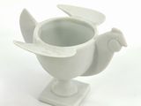 a white vase with a bird on it on a stand