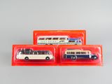 trois bus miniatures sont posés dans des boîtes en plastique sur une table