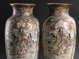 pair of asian vases with figures on them against a black background