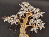 gold tone tree brooch with clear crystal stones on a black background
