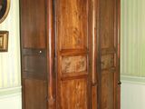 une grande armoire en bois dans une pièce où est accrochée une horloge au mur