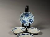 four blue and white plates and a bowl on a stand